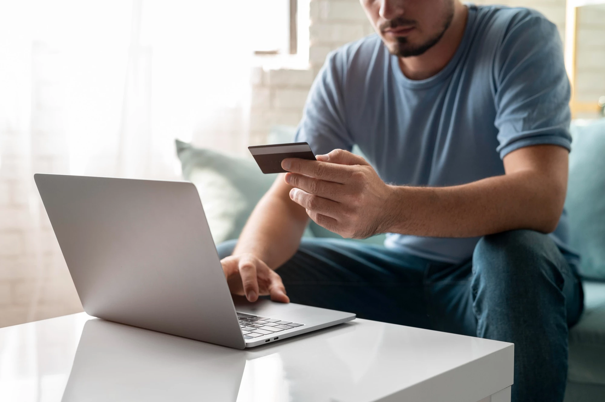 man entering card details while online shopping on laptop