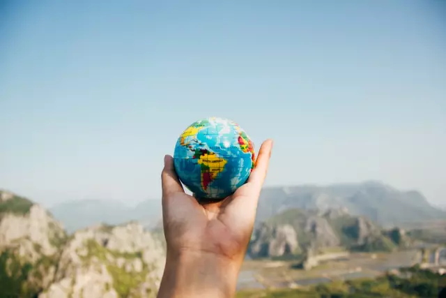 Hand holding a small globe showing South America.